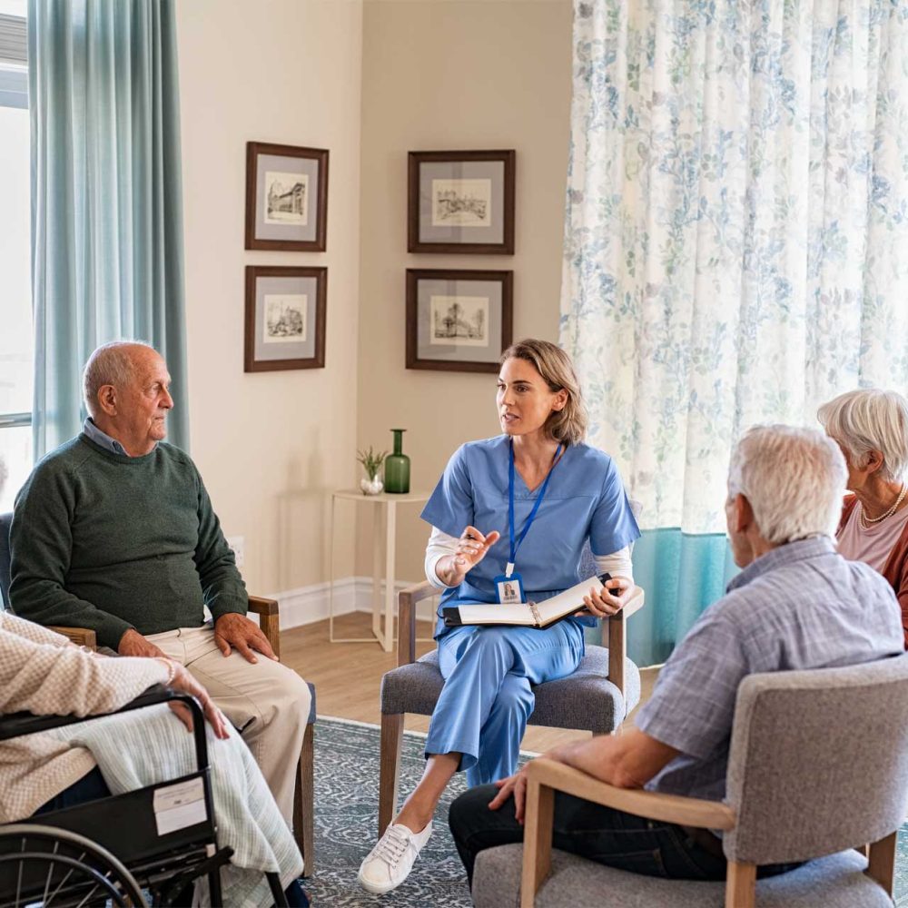 park manor nurse talking to senior people during group therapy